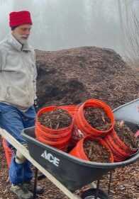 Volunteer moving mulch in wheelbarrow on a foggy day.